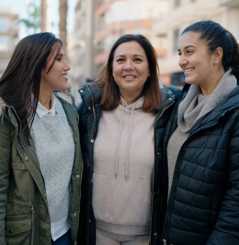 Mother and daugthers smiling confident hugging each other at street